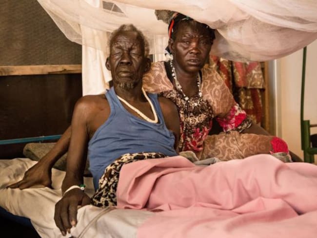 Una mujer se sienta junto a su marido, un paciente del hospital de MSF en el centro de protección civil de Malakal, en Sudán del Sur. Marzo 2019