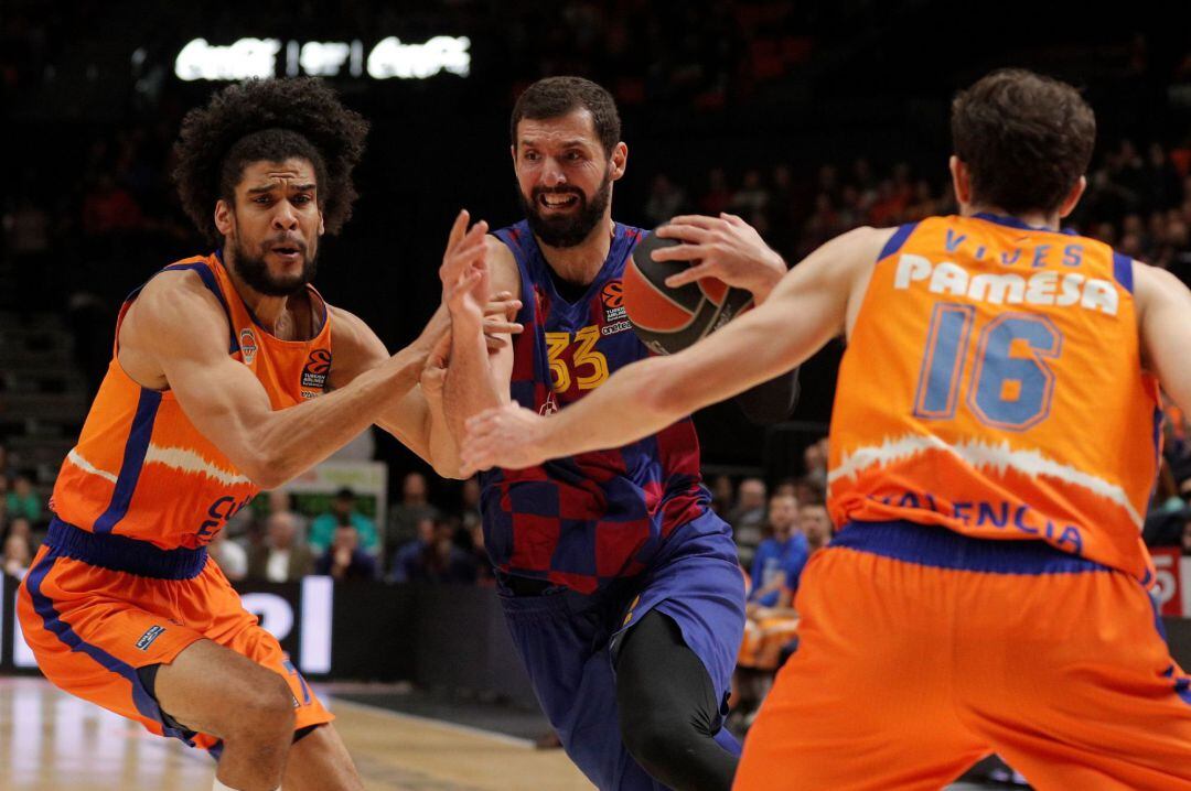 Los jugadores del Valencia Basket,Louis Laberyrie (i) y Guillem Vives (d) Nikola Mirotic (c) , del Barcelona, durante el encuentro correspondiente a la jornada 23 de la Euroliga que se ha disputado en la cancha de la Fuente de San Luis de València.