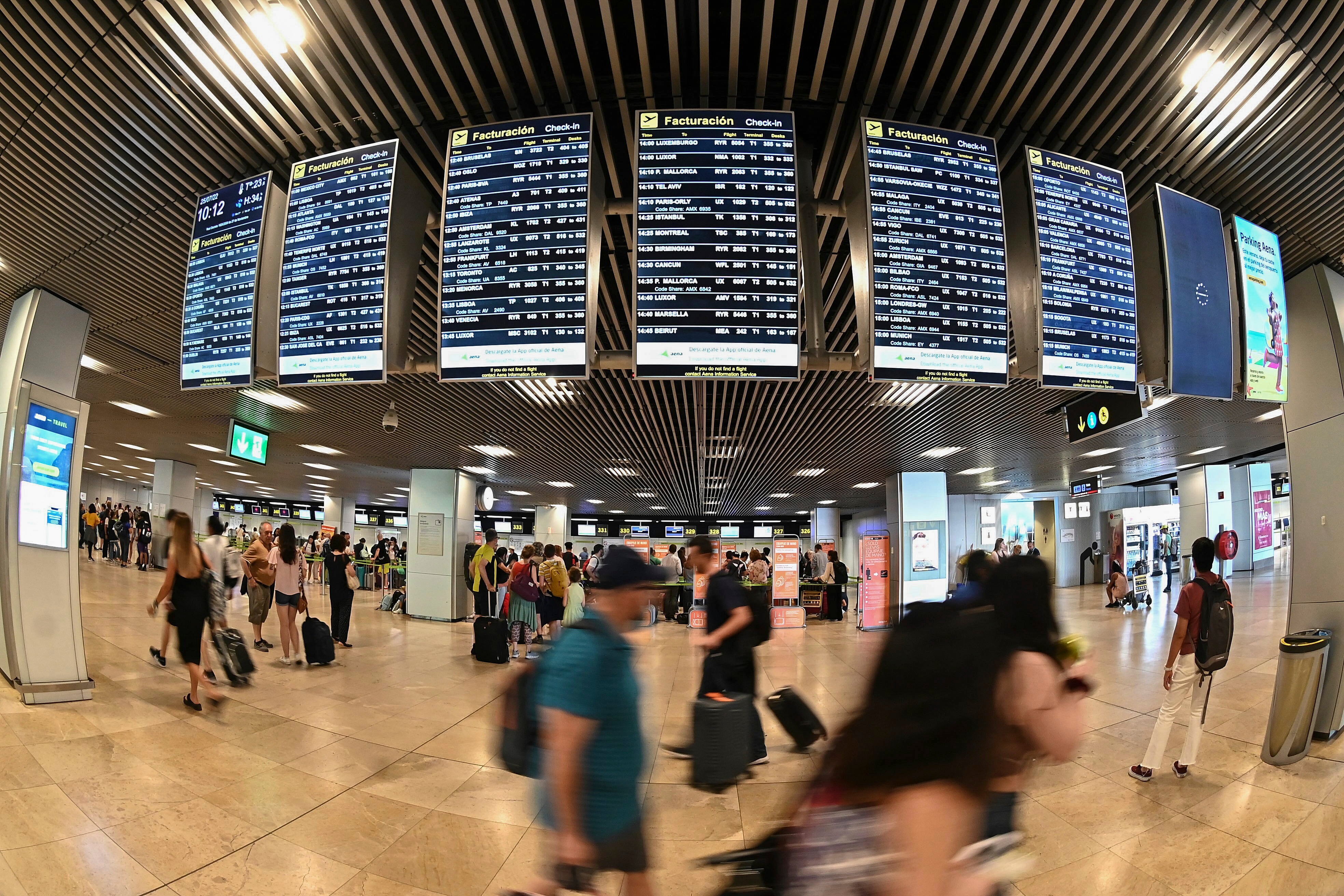 Varios pasajeros pasan por las pantallas de información en el aeropuerto Adolfo Suárez Madrid-Barajas