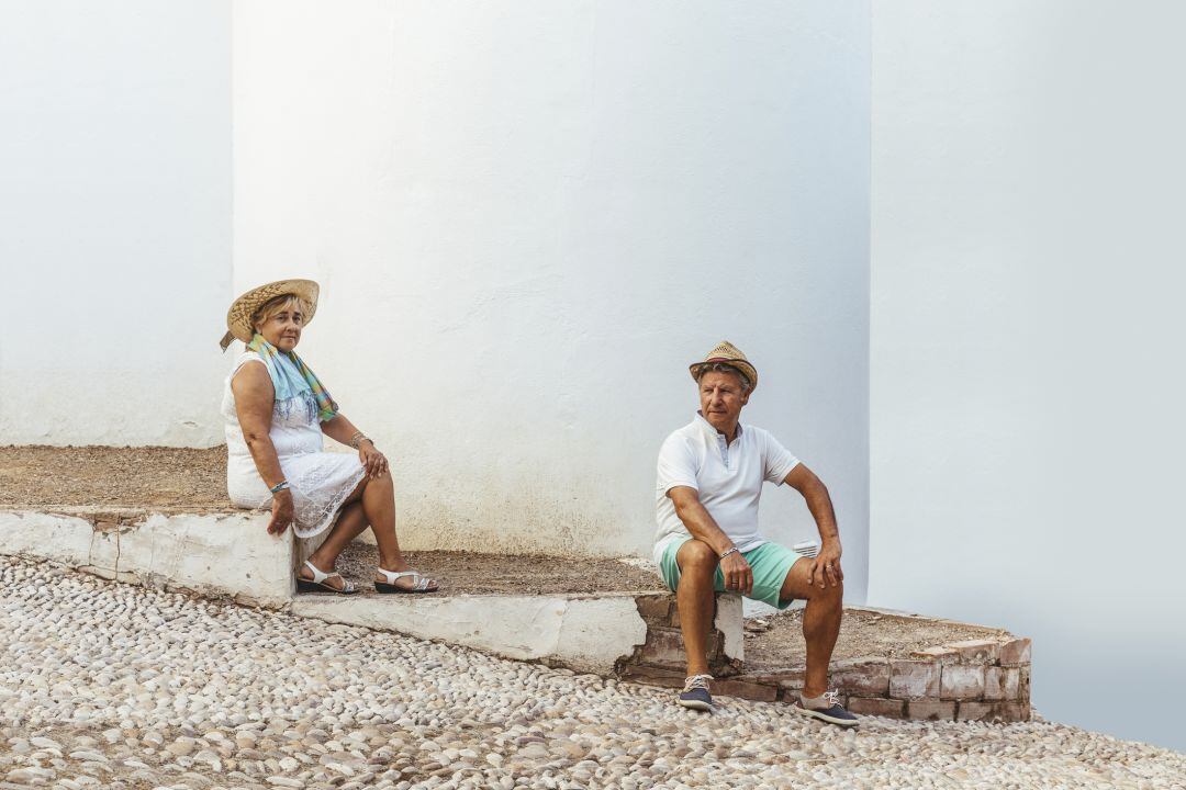 Dos vecinos charlan al fresco en un pueblo español.