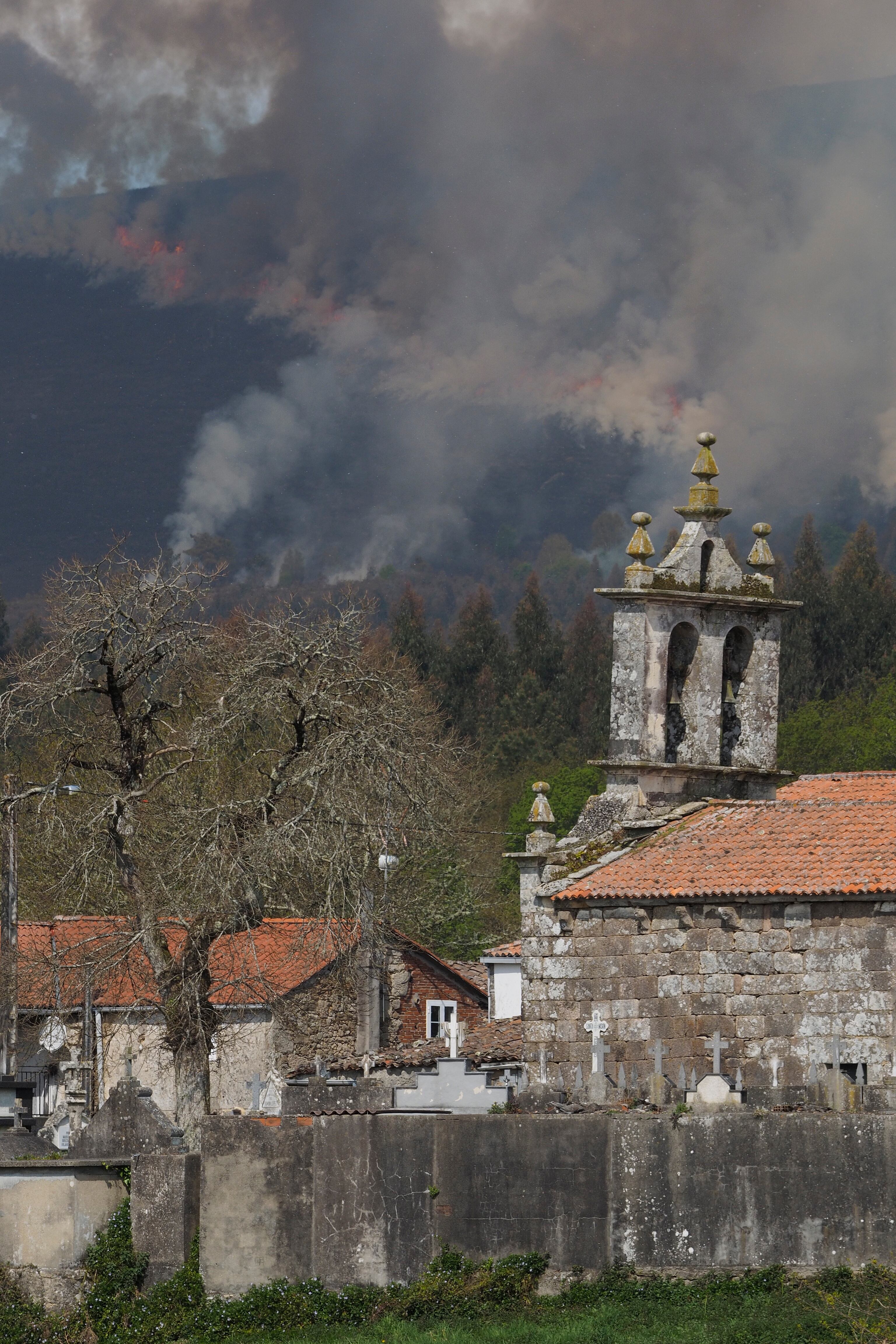 GRAF2404. LUGO, 17/04/2022.- El incendio forestal que se declaró a las 5:27 de la madrugada en el municipio lucense de Palas de Rei, parroquia de Moredo, afecta ya a unas 150 hectáreas, según la última estimación provisional de la Consellería de Medio Rural. En la imagen, vista del incendio en la Sierra Careón, visto desde el pueblo, O Carballal. EFE/ Eliseo Trigo
