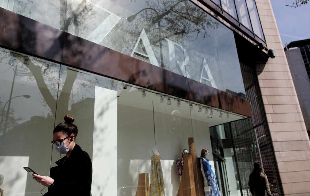 Una mujer con mascarilla pasa junto al escaparate de la tienda Zara de la Calle Princesa de Madrid del grupo Inditex