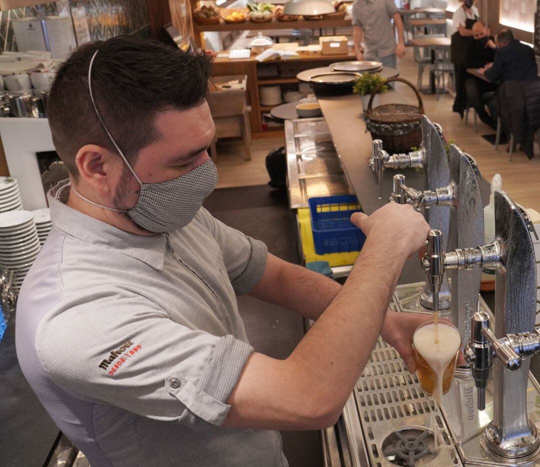 Un camarero llena un vaso de cerveza en un restaurante