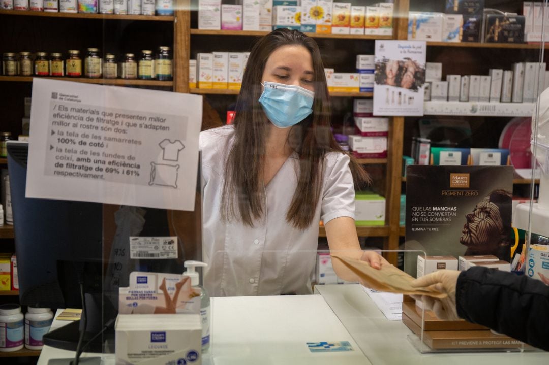 Una farmacéutica entrega un paquete de mascarillas  
 