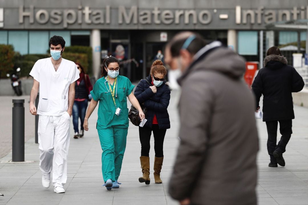 Trabajadores de la sanidad con mascarillas caminan junto a la entrada del hospital La Paz de Madrid este jueves durante la cuarta jornada laboral de aislamiento para frenar el avance del coronavirus.