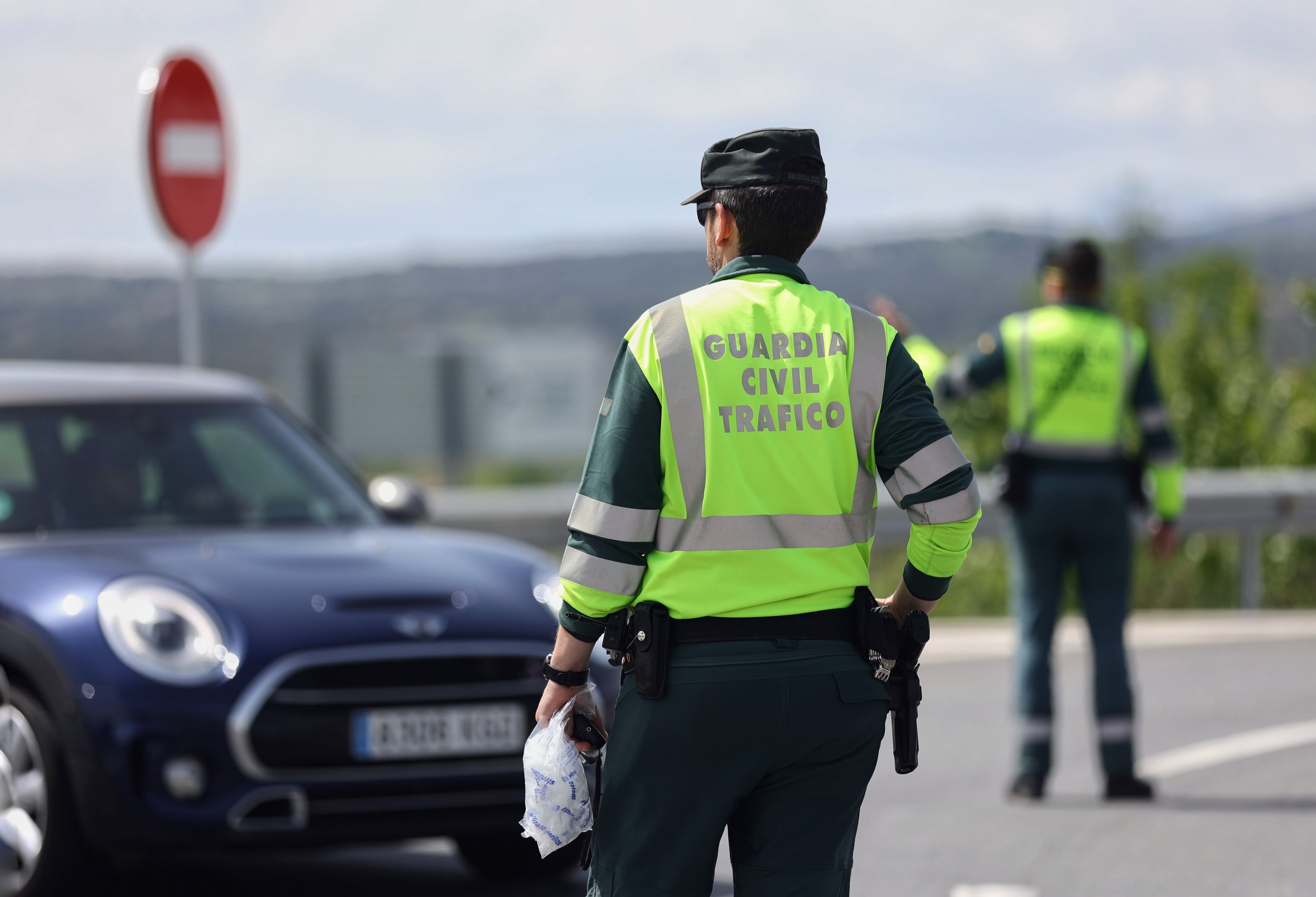 Un guardia civil de tráfico frente a un vehículo.