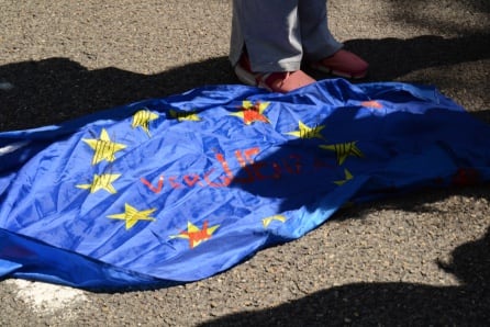 Bandera de Europa en la que puede leerse la palrba &quot;vergüenza&quot; rodeada de concertinas en protesta por las muertes en las fronteras terrestres.