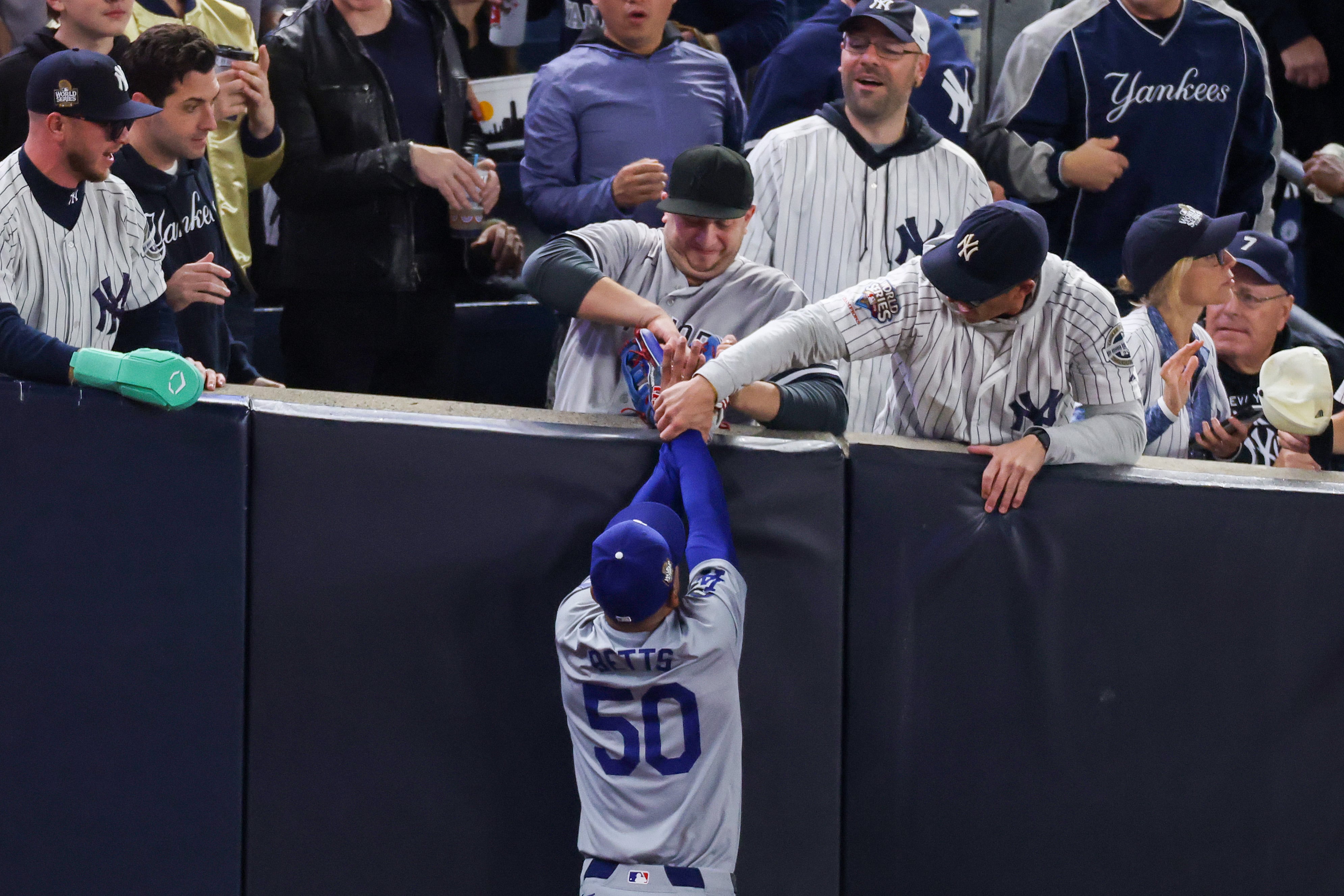 Dos aficionados intentan robar la pelota a Mookie Betts