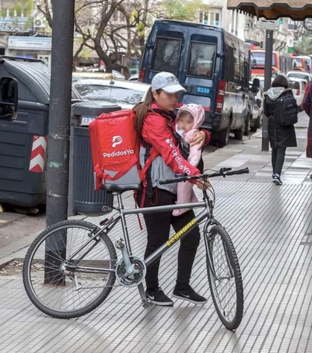 La repartidora con su hijo sobre su pecho fotografiada en Buenos Aires, Argentina.