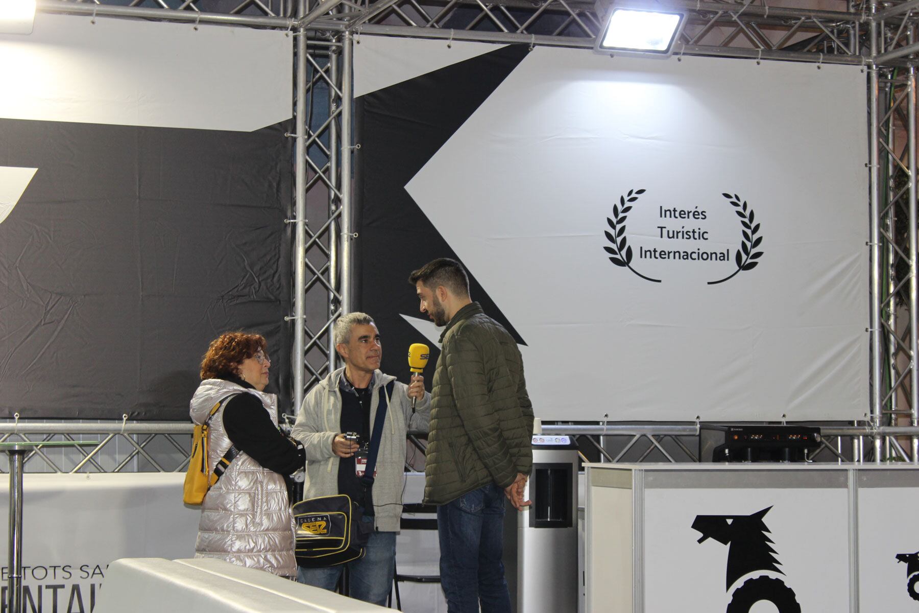 L&#039;alcalde de Cocentaina, Jordi Pla, i la regidora de Fira, Marcela Richart, atenent al micròfon de Ràdio Alcoi en el stand de premsa