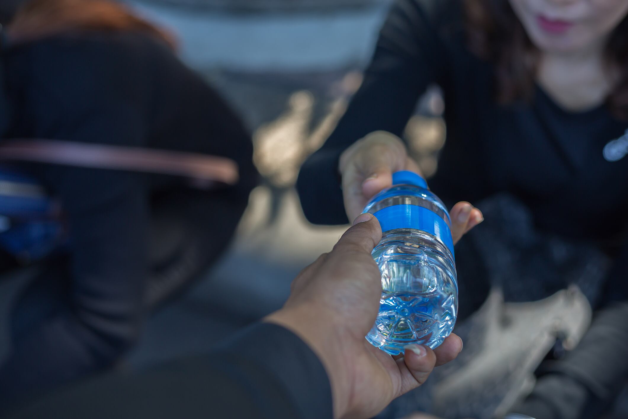 Una persona entrega una botella de agua a otra