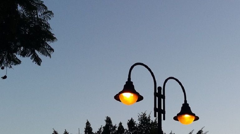 Farola encendida con los primeros rayos del amanecer