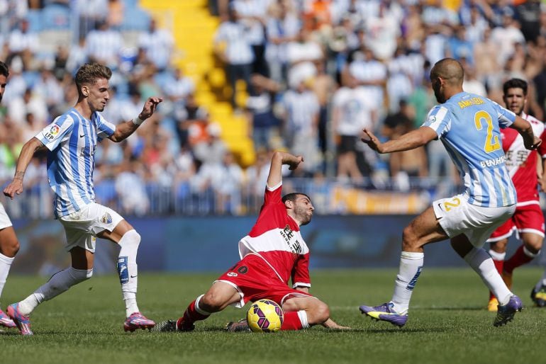 GRA141. MÁLAGA, 26/10/2014.- El centrocampista y capitán del Rayo Vallecano Roberto Trashorras (c), cae ante los delanteros del Málaga, Samuel Castillejo (i) y el neerlandés-marroquí Nordin Amrabat, durante el encuentro de la novena jornada de Liga de Primera División que los dos equipos disputan en el estadio de La Rosaleda, en Málaga. EFE/Jorge Zapata