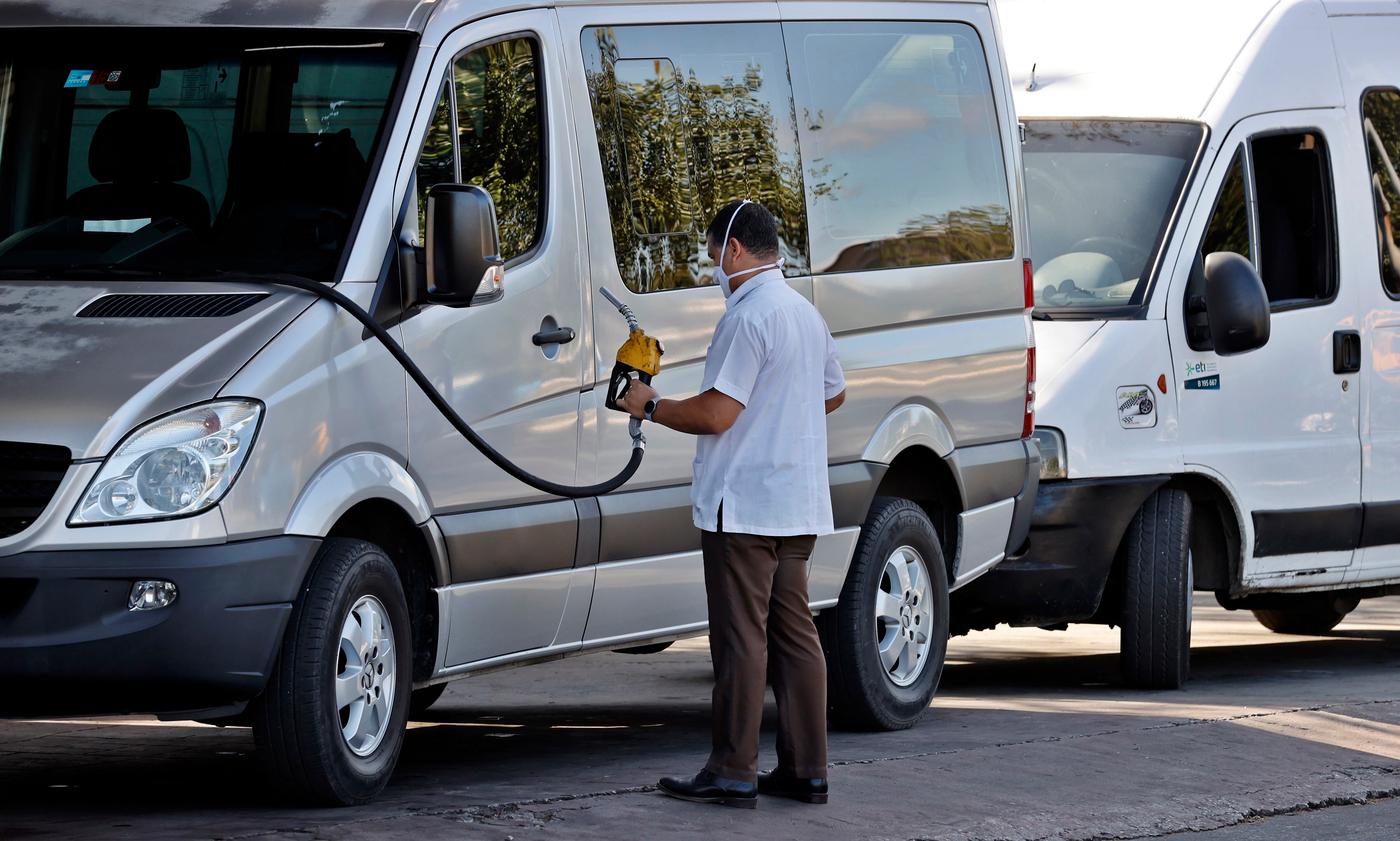 Un hombre es visto mientras abastece de combustible su vehículo,