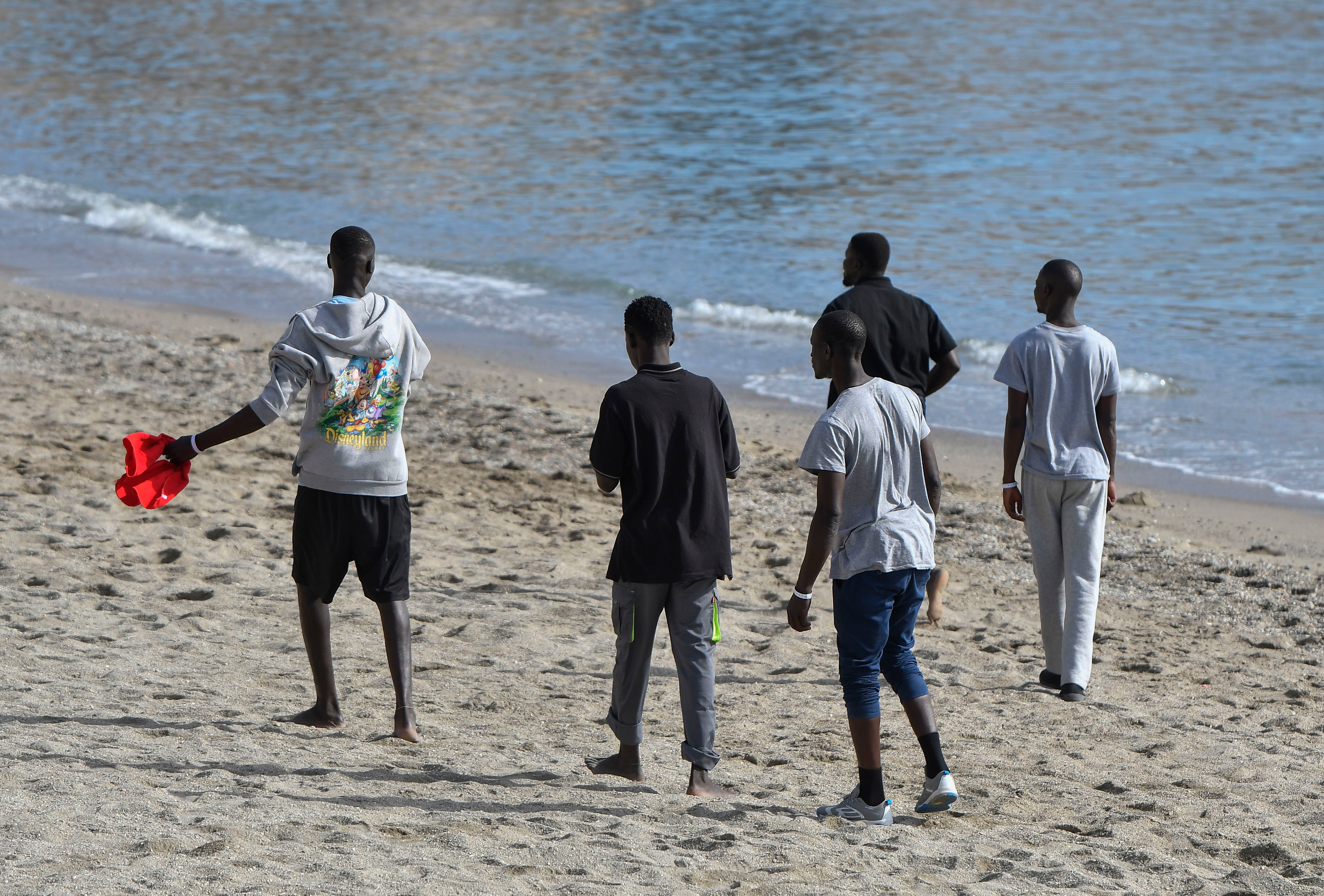 ALMERIA 29/10/2023. Varios de los inmigrantes subsaharianos trasladados desde Canarias, pasean por la playa frente al hotel donde están realojados en Aguadulce, Roquetas de Mar (Almeria). EFE / Carlos Barba
