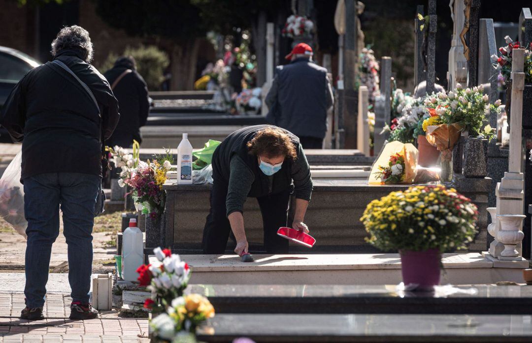 Una mujer limpia la lápida de una tumba del cementerio de Alcalá de Henares, días antes de la celebración del Día de Todos los Santos el próximo 1 de Noviembre.