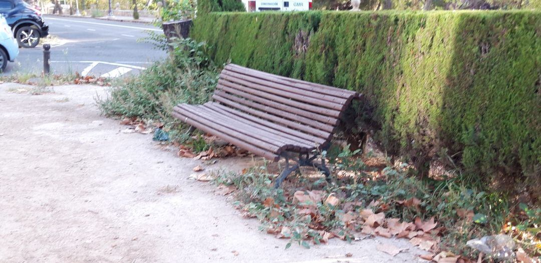 Banco lleno de maleza en los jardines del entorno de la Gran Vía de València