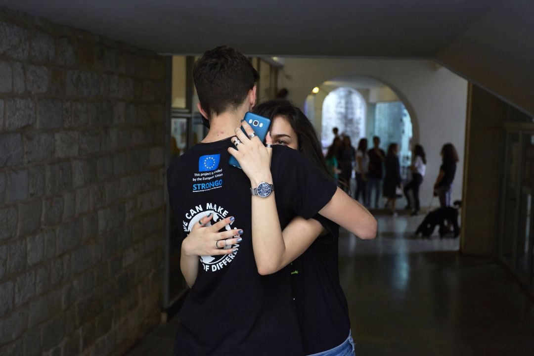 Una joven mira su teléfono mientras abraza a un chico