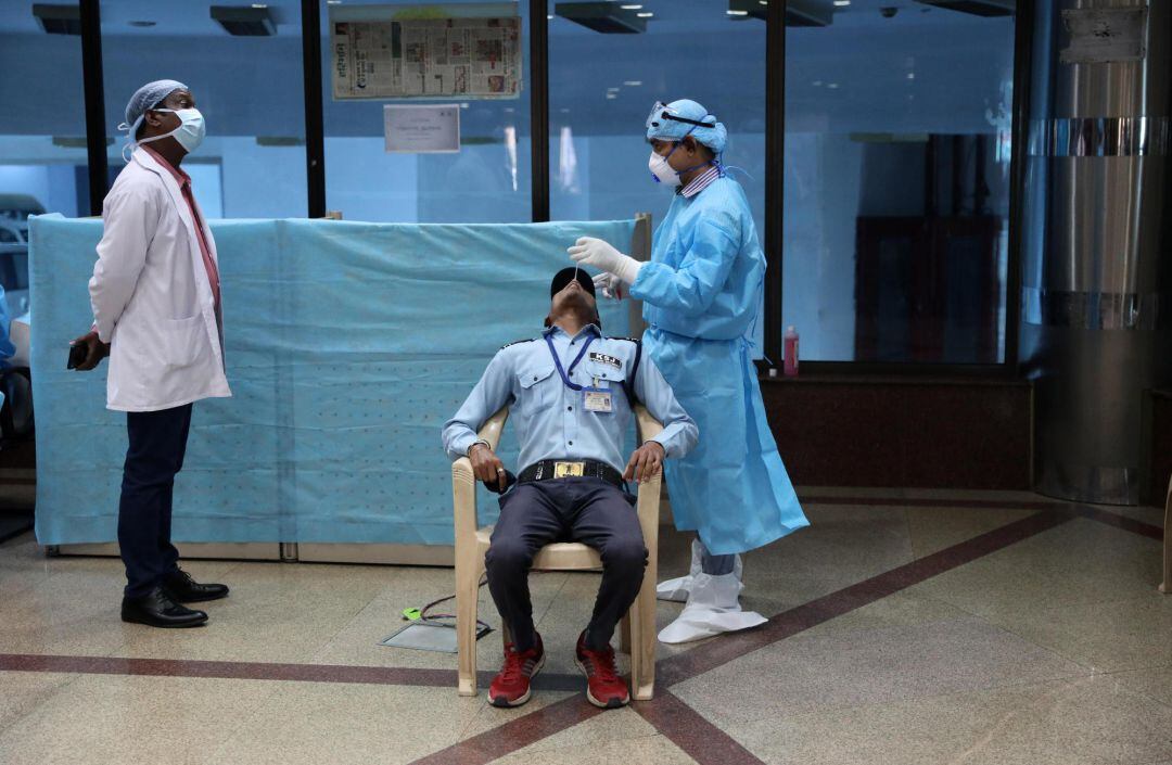 A health worker collects a swab sample from a person for a COVID-19 RT-PCR test
