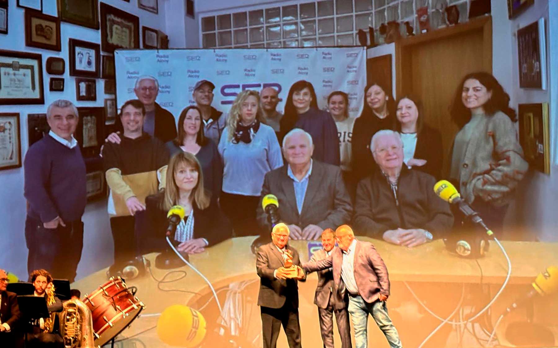 Instante en el que Juan Jordá recoge el premio con una imagen de los componentes de Radio Alcoy proyectada sobre el escenario del Teatre Calderón