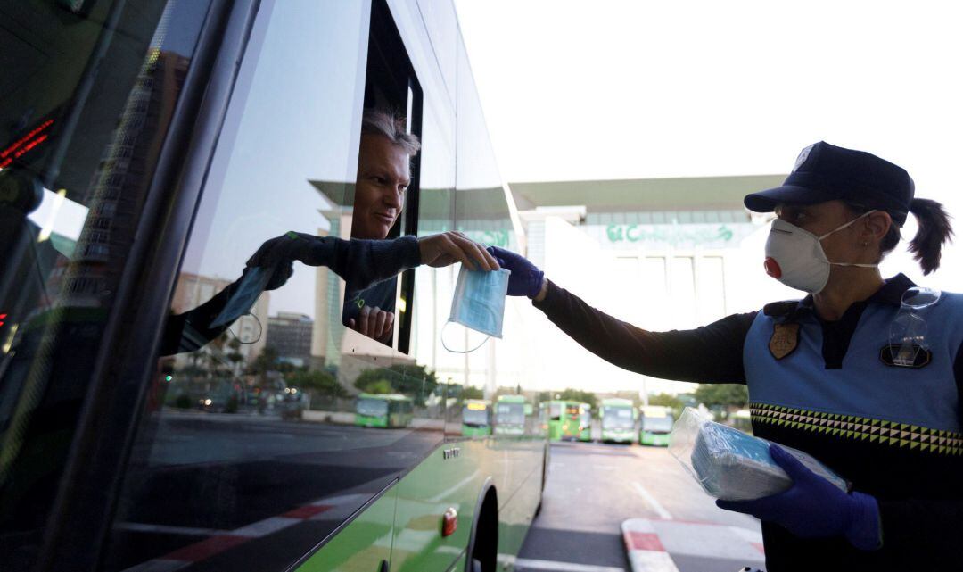 Agentes de la Policía Local de Santa Cruz de Tenerife reparten mascarillas en el intercambiador de autobuses.