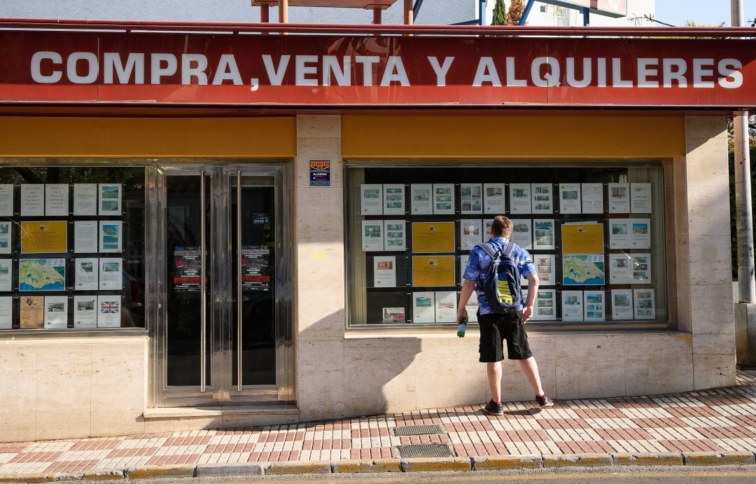 Un joven mira el escaparate de una inmobiliaria