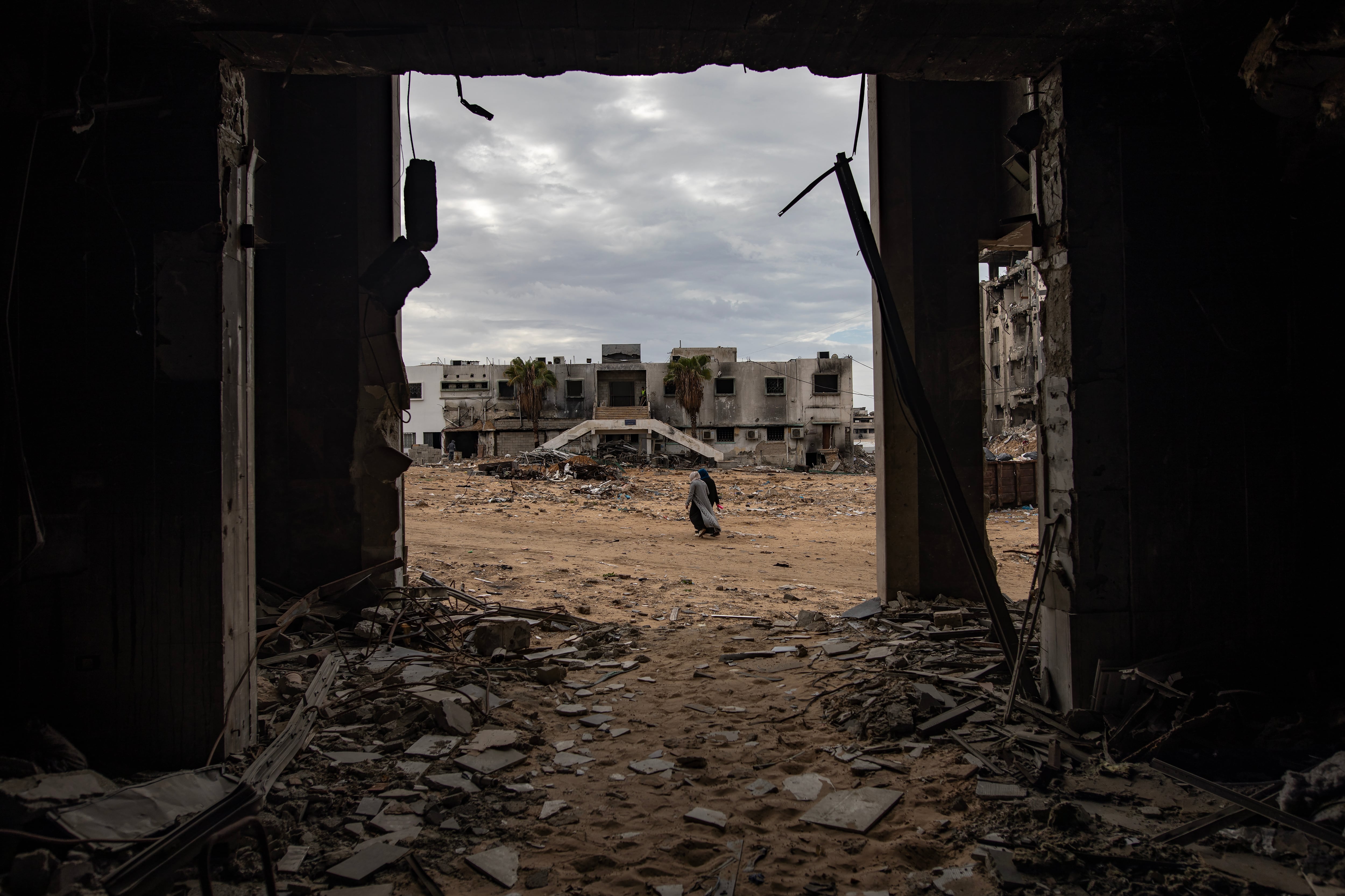 Dos personas caminan entre los escombros del hospital dañado de Al-Shifa, en medio del alto el fuego entre Israel y Hamas, en la ciudad de Gaza, este miércoles