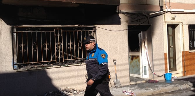 Un policía municipal camina delante de la vivienda afectada por el incendio de Sabadell