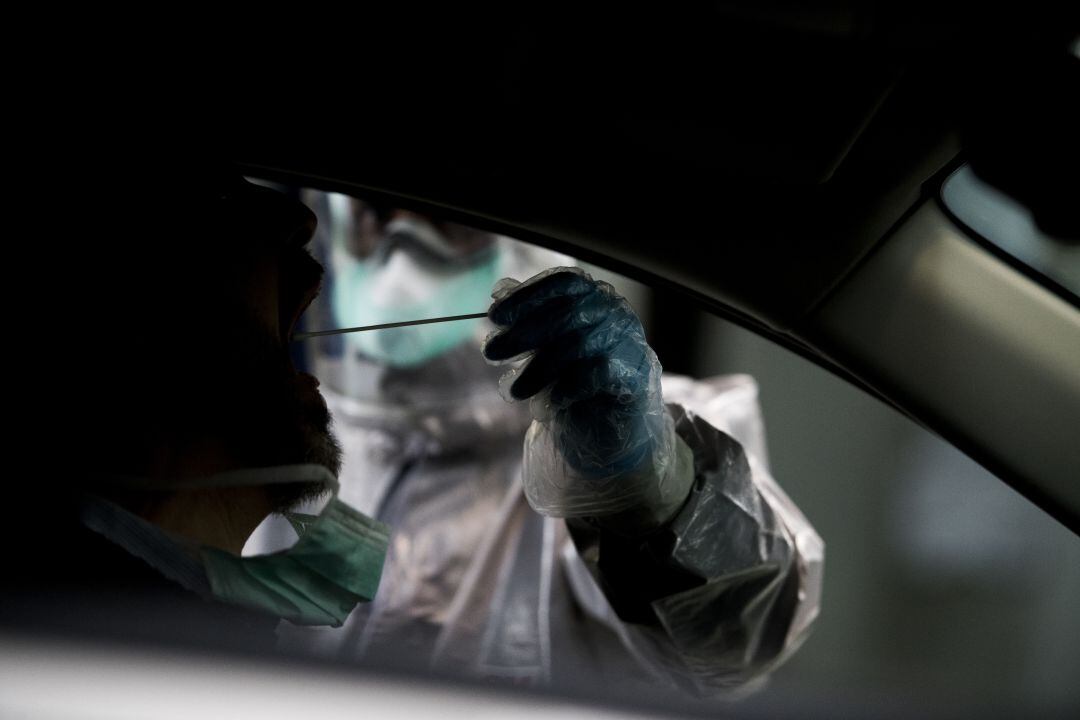 Un sanitario realizando una prueba PCR a un ciudadano en su coche. 