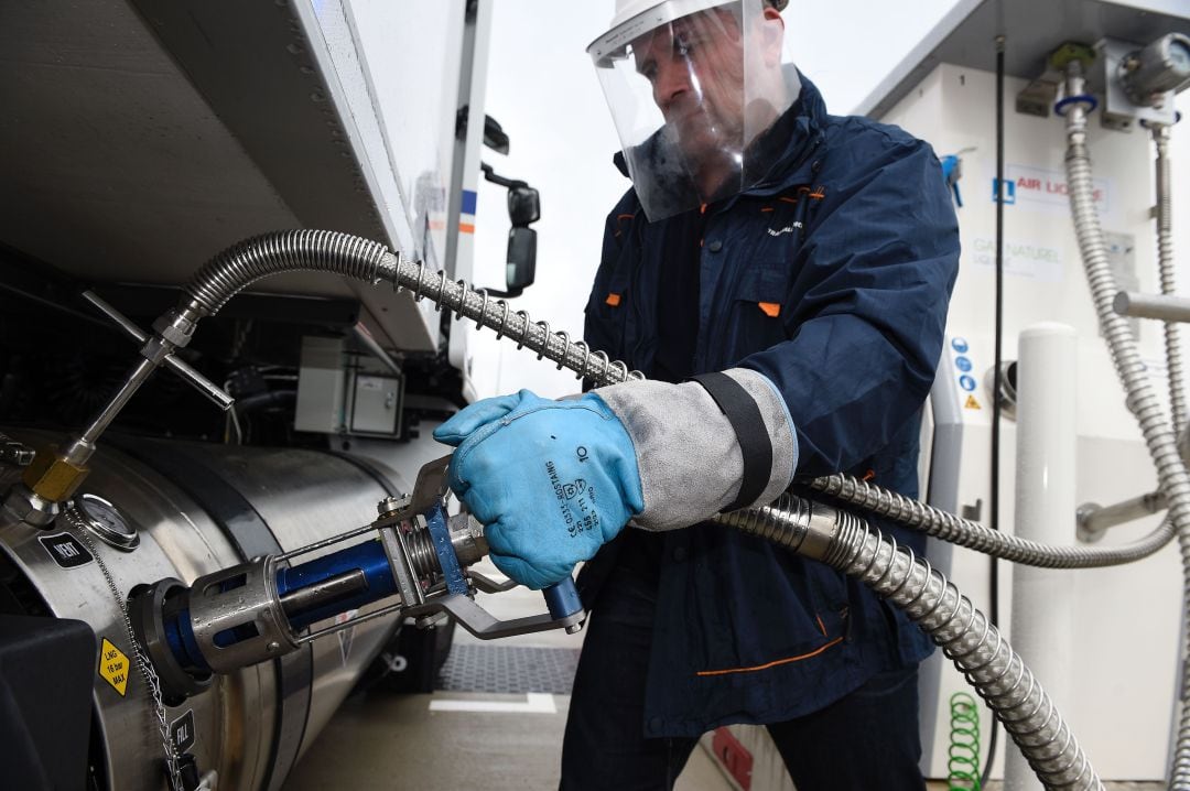 Un trabajador llena un camión con gas natural licuado en la gasolinera