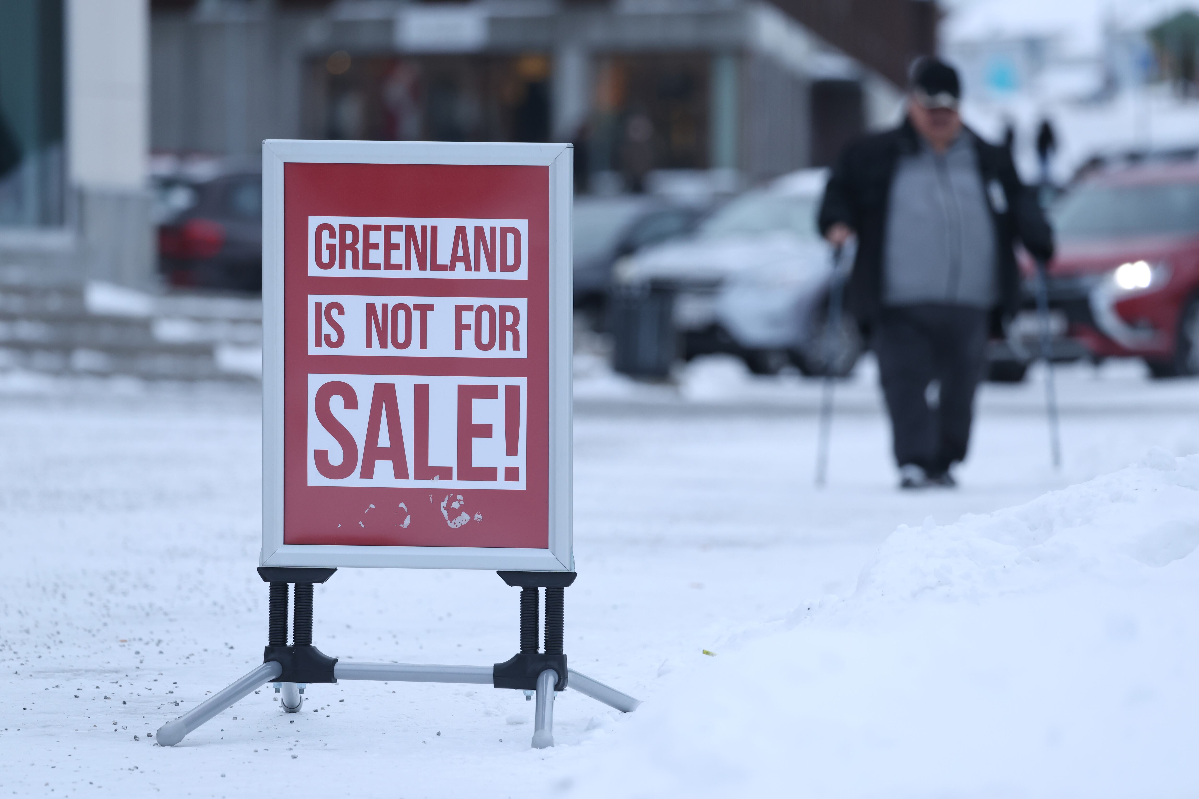 Un hombre camina por la capital de Groenlandia, Nuuk, junto a un cartel donde se lee "¡Groenlandia no se vende!"