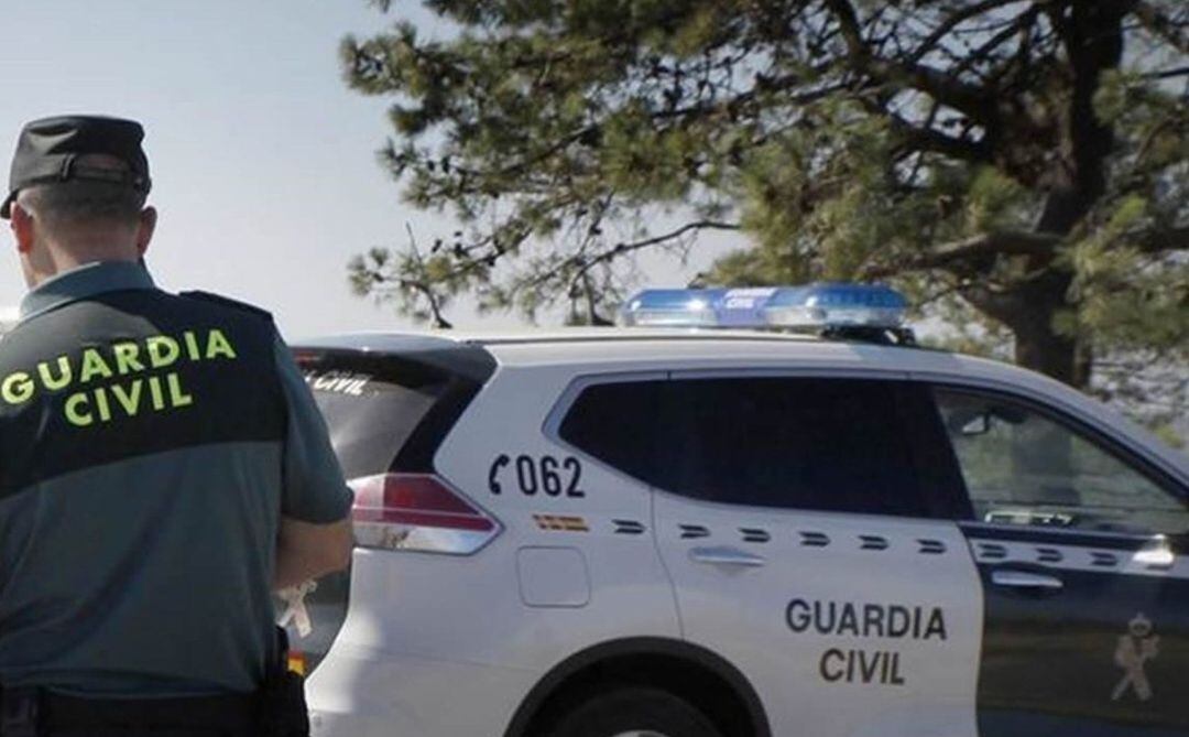 Un agente de la Guardia Civil junto al vehículo patrulla.