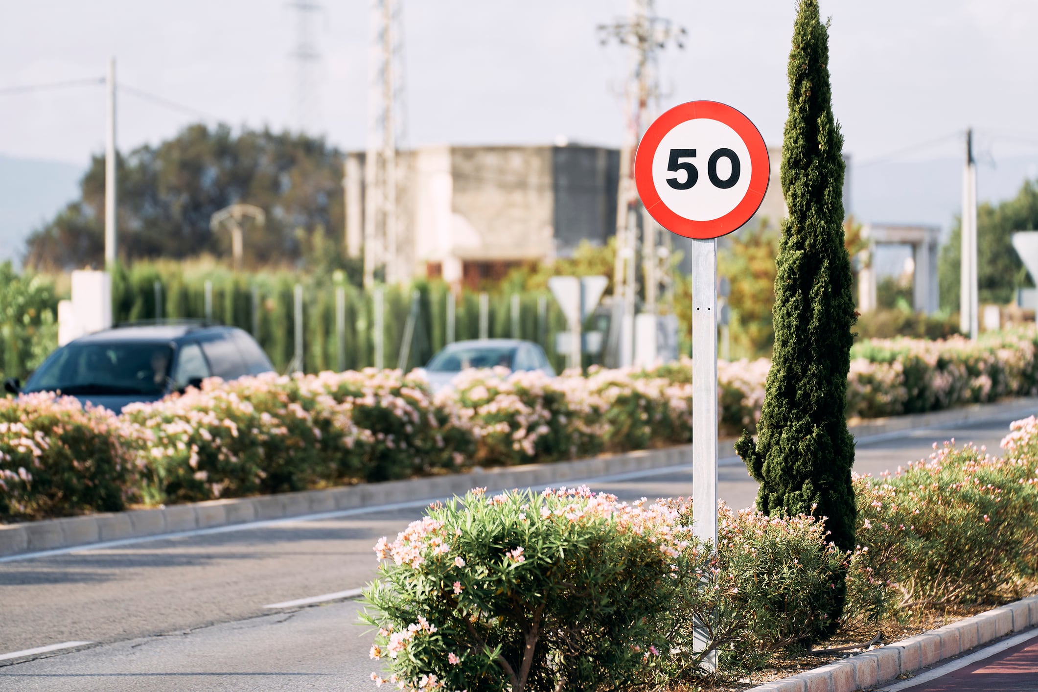 front view of a red round sign with a number inscribed on the street pole with cars on one side