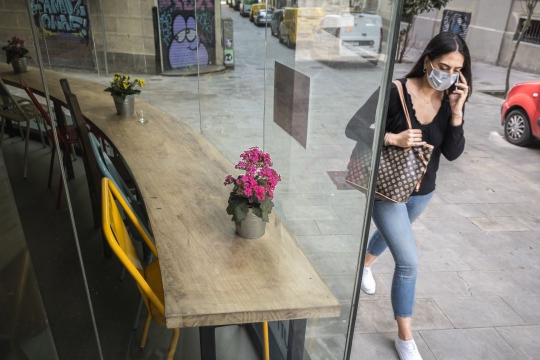 Una mujer camina frente a un escaparate en una calle de Barcelona