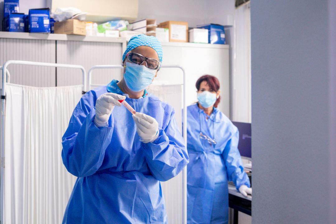 Un trabajador sanitario protegido sostiene una de las probetas utilizadas para la realización de tests PCR, foto de archivo