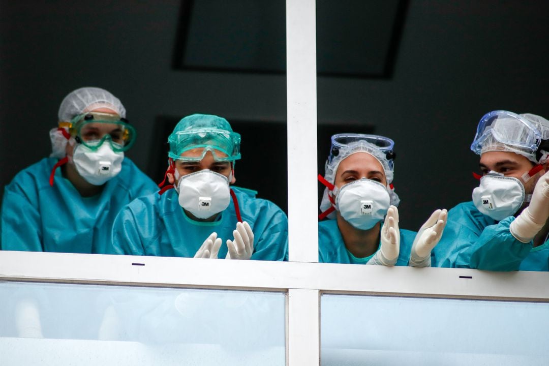 Varios sanitarios con protección EPI, mascarillas, gafas y guantes, aplauden en agradecimiento desde la ventana el homenaje a los Sanitarios celebrado en el Hospital Fundación Jiménez Díaz.