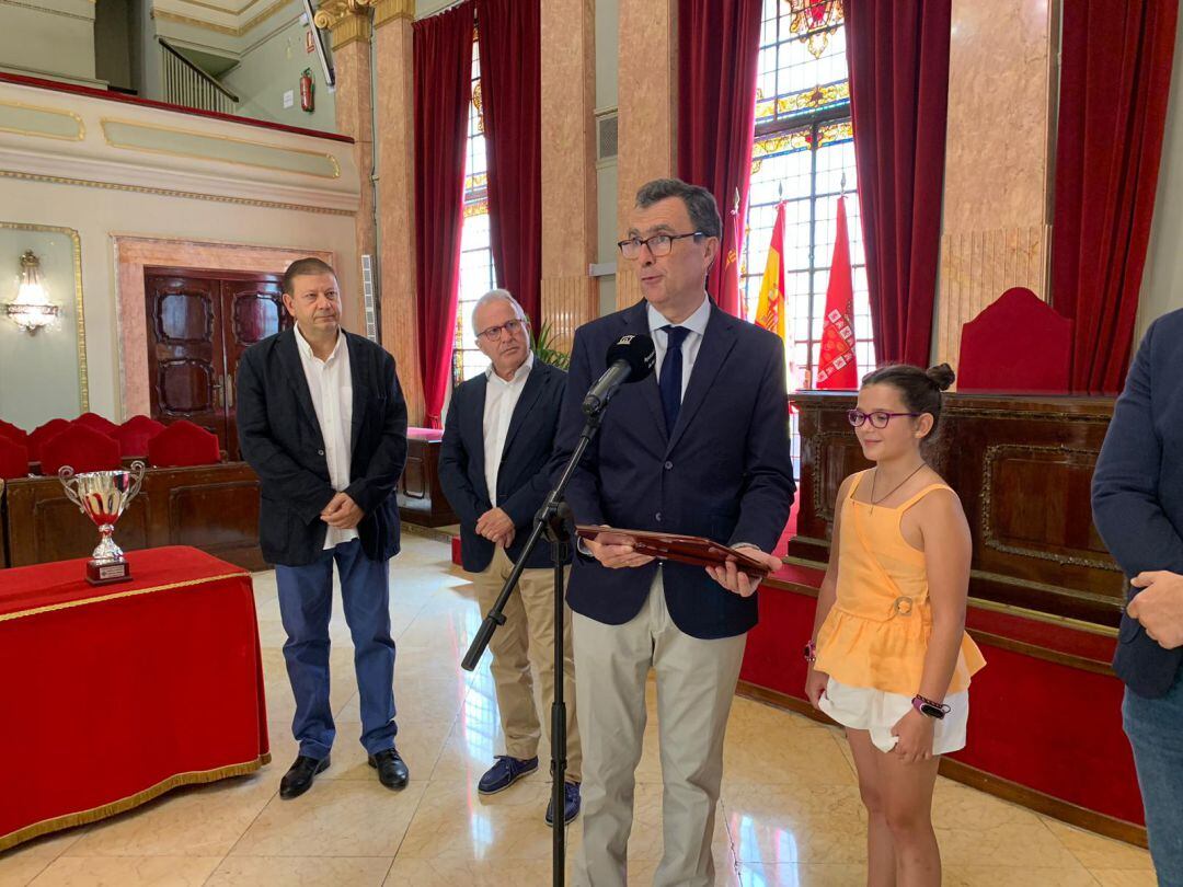 El alcalde de Murcia, José Ballesta, en el momento de entregarle la placa a Elena Rodríguez, la niña doblemente campeona de España de ajedrez en la categoría benjamín