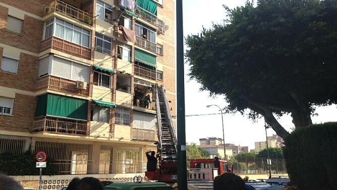 Los bomberos retiran parte del material dañana en el balcón de la vivienda