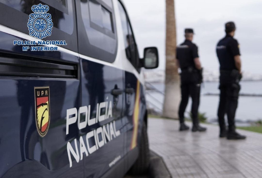 Agentes de la Policía Nacional junto a un coche patrulla.