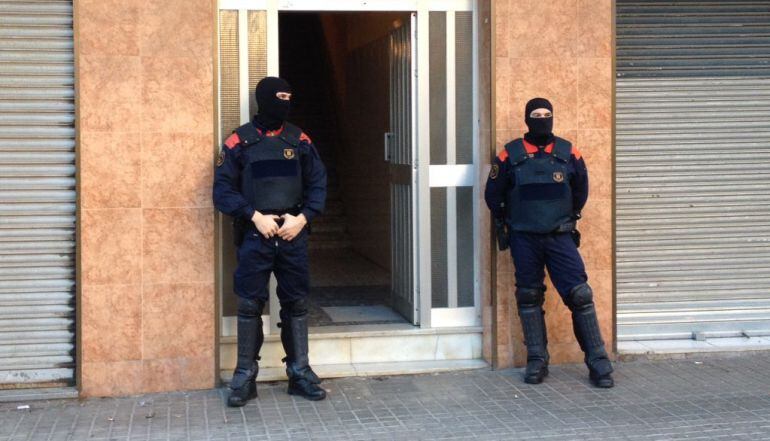 Los Mossos custodian la puerta de uno de los edificios registrados en la Operación Bennu contra el tráfico de mujeres  