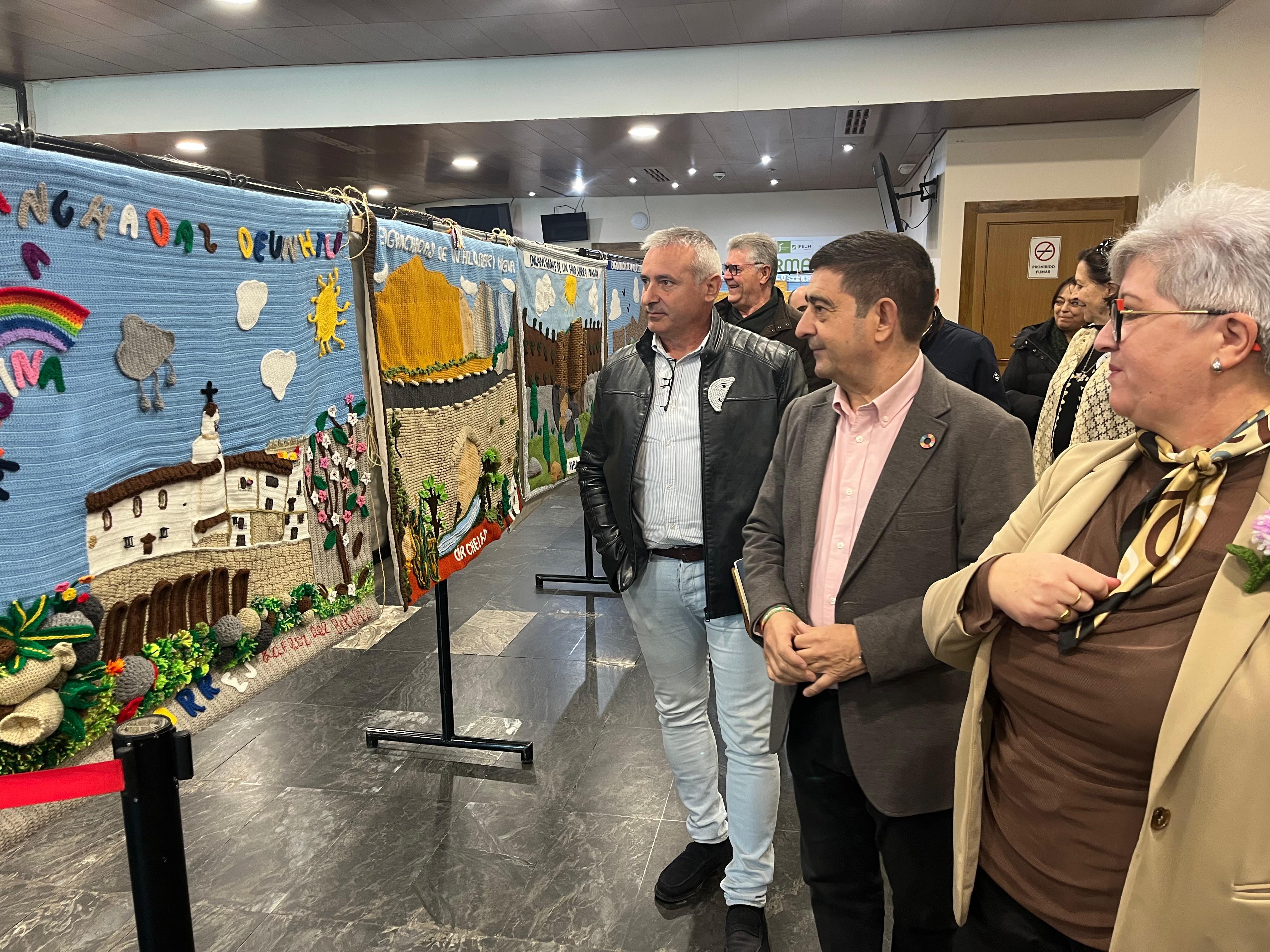 Visita de Paco Reyes a la exposición en IFEJA, acompañado por el presidente de la ADR Sierra Mágina, Antonio Morales, y mujeres que han participado en la iniciativa 'Enganchadas por un hilo'