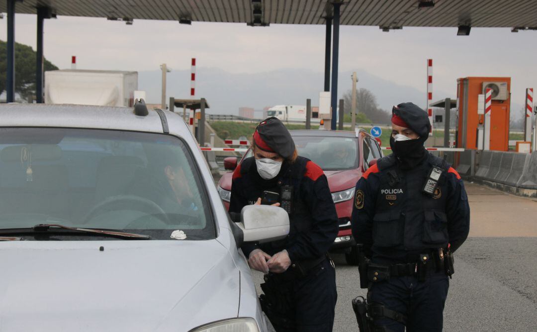 Una mossa d'esquadra revisa la documentació que li facilita un dels conductors que passa pel peatge de Maçanet de la Selva aquest dissabte 21 de març de 2020