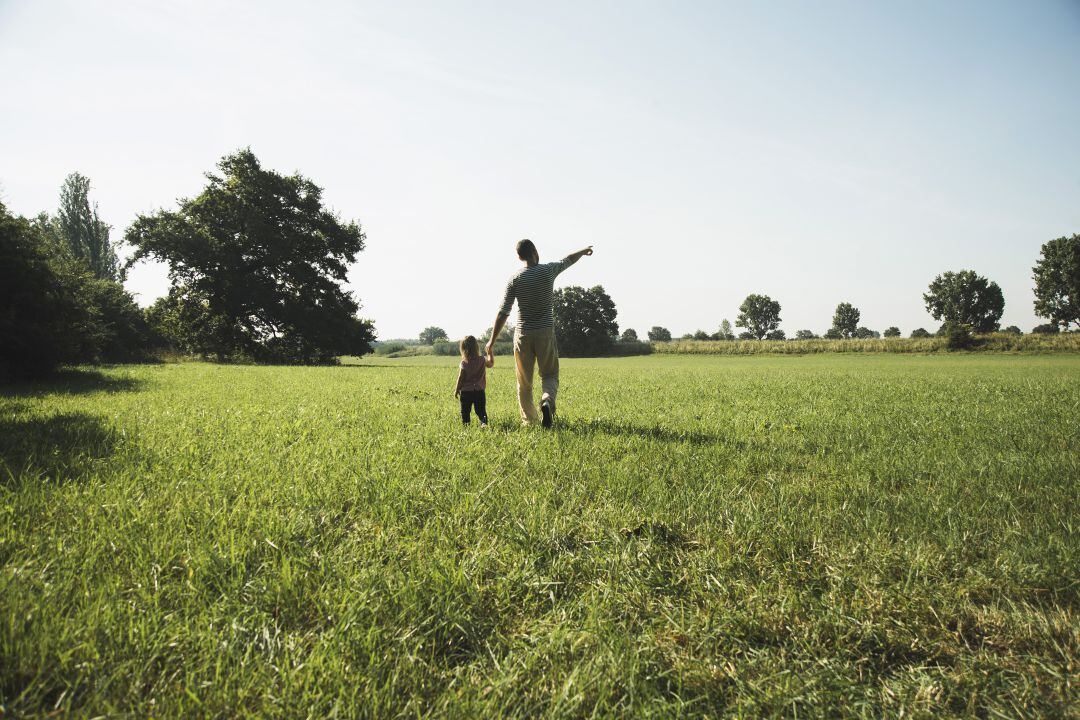 Un niño paseando por el campo con su padre