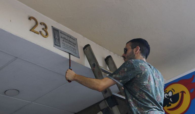 Imatge d'un jove despenjant una placa. 