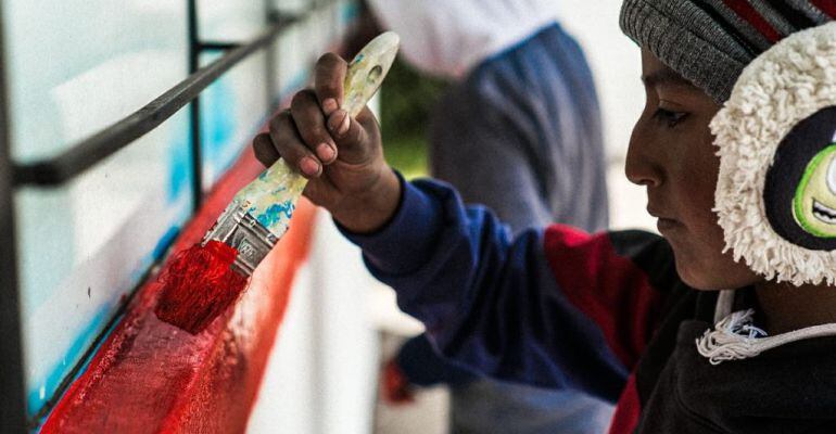 Un menor pinta con una brocha las instalaciones de su escuela en Ecuador.