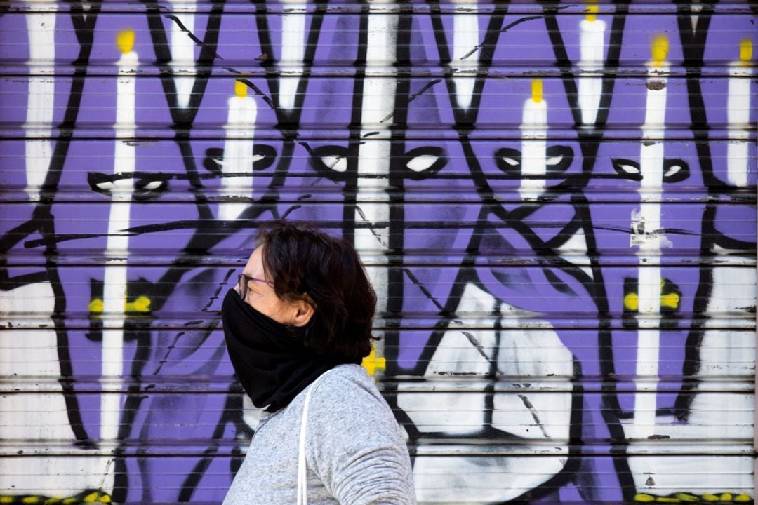 Una mujer camina delante de un mural sobre la Semana Santa en Málaga