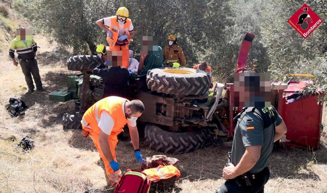Los sanitarios y bomberos atendiendo al hombre herido tras volcar con su tractor en Planes.
