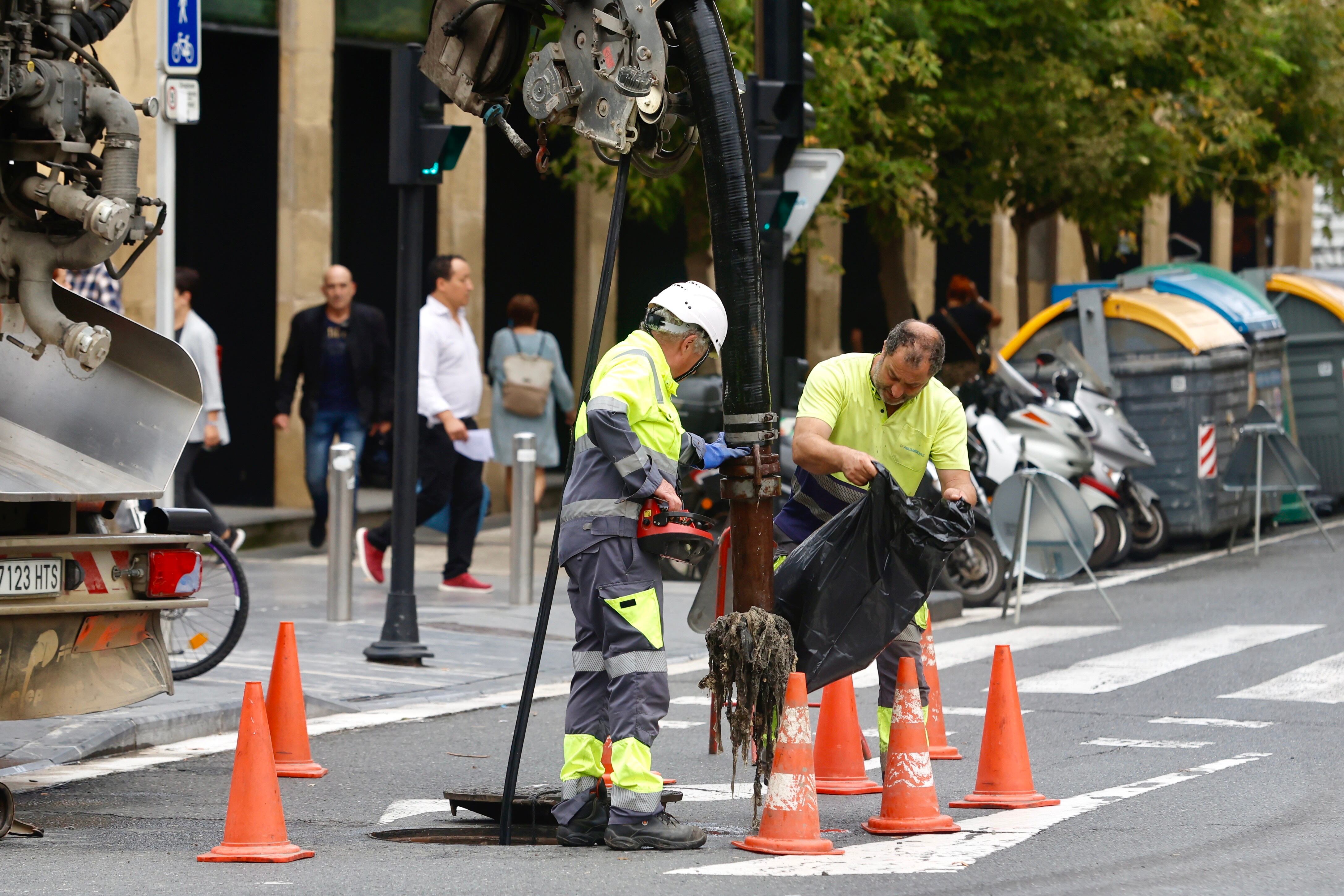 SAN SEBASTIAN, 03/10/2023.- Dos trabajadores retiran residuos de una alcantarilla este martes en San Sebastián. Según los datos de desempleo de septiembre, dados a conocer este martes, el 40,4 % de las personas en desempleo son de larga duración, es decir, llevan más de un año buscando empleo. EFE/Javi Colmenero
