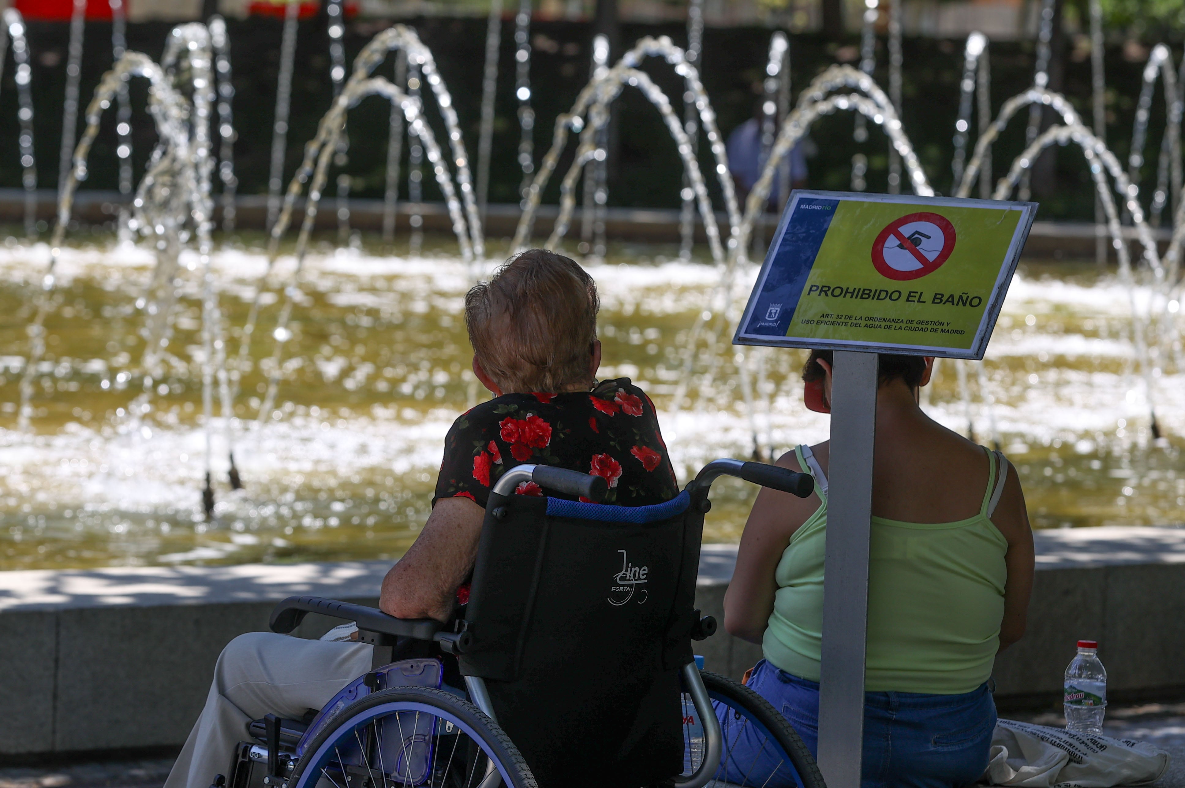 Un grupo de personas se refresca a la sombra, junto a las fuentes del parque del Retiro en una jornada marcada por las altas temperaturas.