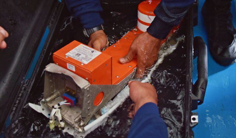 Buzos de la marina manipulan la caja negra del avión de AirAsia que encontraron este lunes en el fondo del mar